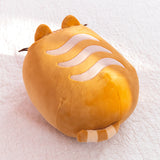 Back view of the loaf squisheen. The oval shaped plush has light cream wavy stripes on the top of the plush. At the back bottom of the plush is a light brown and cream striped tail. 