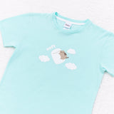 A close-up view of the pajama tee on a white background. The mint green pajama tee features a Pusheen, a white marshmallow, three fluffy white couds, and the phrase “soft." 
