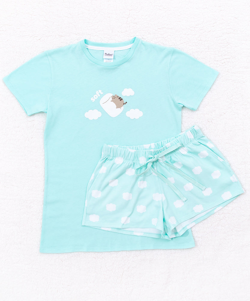 Marshmallow Dreams Pajama Set includes a mint green short sleeve shirt with Pusheen graphic with clouds that match the pattern of the mint green lounge shorts. The Pusheen the Cat shirt graphic shows Pusheen riding a marshmallow and remarking on how soft it is. 