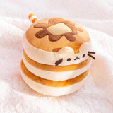 Top quarter view of pancake squisheen plush. Pusheen’s light brown and cream striped tail extends from the back of the stacked plush.