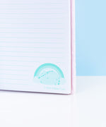 Close-up view of one of the light teal graphics located at the bottom of the interior, teal-lined pages. The light teal graphic features Pusheen winking. The copyright information for Pusheen Corporation is included under the graphic. 