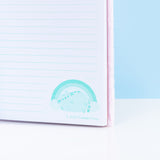 Close-up view of one of the light teal graphics located at the bottom of the interior, teal-lined pages. The light teal graphic features Pusheen winking. The copyright information for Pusheen Corporation is included under the graphic. 