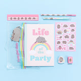 Contents of the Pusheen stationery set laid on a light blue surface. The set includes a light pink ruler, clear zip pouch, a notebook with the phrase “Life of the Party, pen, pencil, sticker sheet, eraser, and pencil sharpener.  