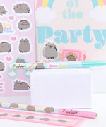 Close-up view of the contents of the Pusheen stationery set. The ruler, pencil, pen, sticker sheet, eraser, pencil sharpener, and notebook include graphics of a grey and brown Pusheen with yellow, pink, blue, and light teal details.  