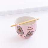The Pusheen Ramen Bowl with the chopsticks resting in the holes of the bowl, in front of a white background.