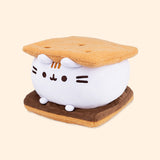 Left quarter view of s’mores-inspired plush. This view shows Pusheen’s white marshmallow feet extending off her body resting atop the chocolate slab.  