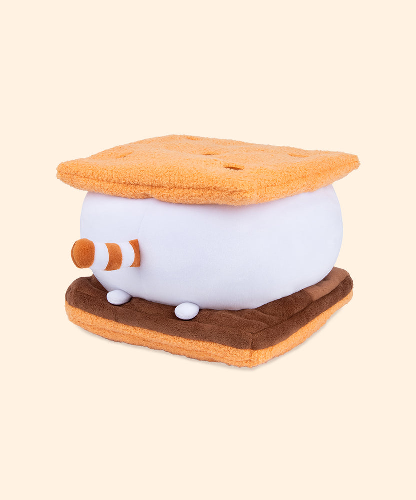 Back view of the s’more squisheen Pusheen’s tail is stripped with light and light brown. White feet extend off the back of the marshmallow and rest atop the chocolate-inspired slab of plush. 