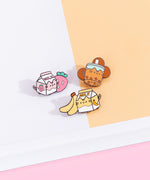 Pusheen Sips Pins are attached to a cardboard backing featuring a grid interior. The pin set is lying on a pink backdrop. 