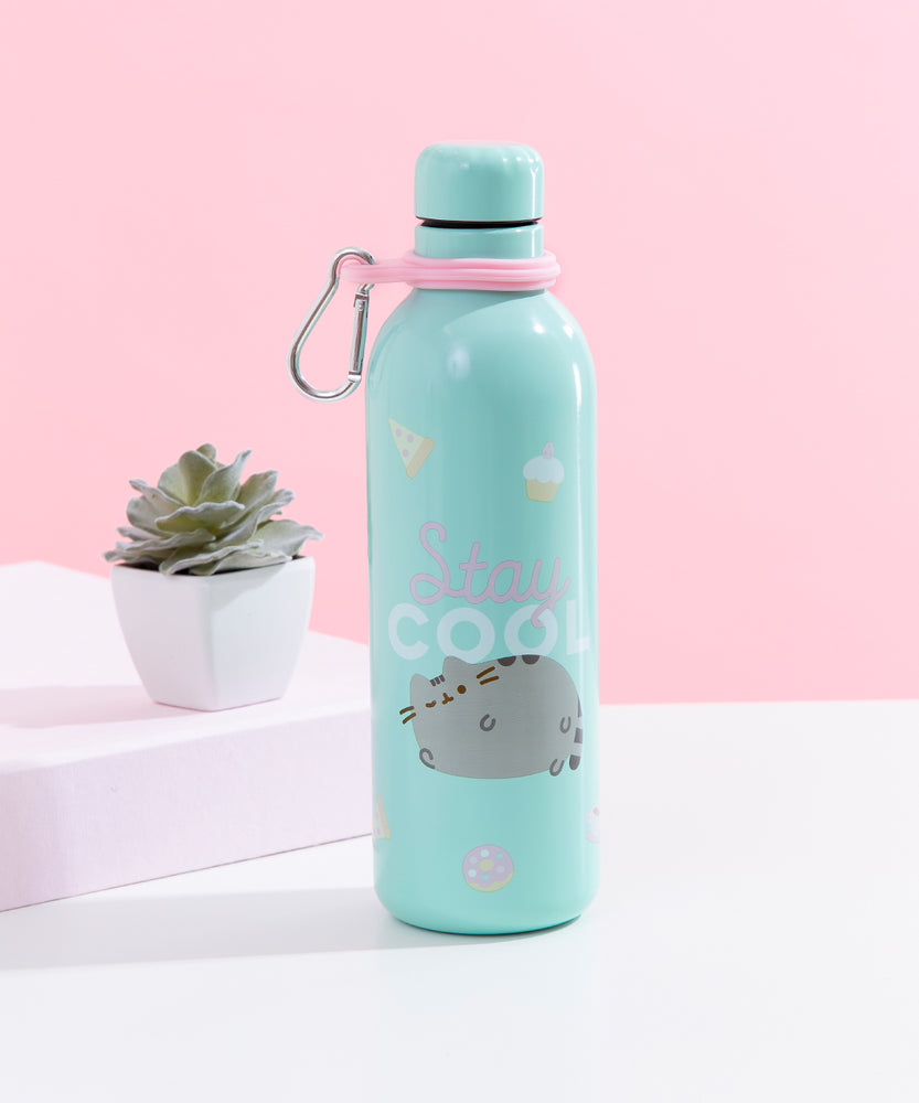A light blue steel water bottle with a round screw-on cap and a pink carabiner loop with a silver snap hook attached, featuring a printed design of Pusheen winking on her side, the words ‘Stay Cool’ above her, surrounded by donuts, pizza and cupcakes. The bottle in front of a white and pink background, with a small succulent besides it.