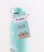 Close up of the hangtag hanging from the Pusheen Stainless Steel Waterbottle. The tag is a similar light blue as the bottle, with the Pusheen logo in a white rectangle near the top, Pusheen at the bottom, and the text ‘Hot and Cold Drink Bottle’ written in cursive in the middle.