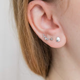 Closeup of a model’s ear wearing the Silver Pusheen Charm Stud Earrings on their lobe, along with their two other piercings that are wearing different silver stud earrings. The Pusheen Stud earring is bigger then a simple dot earring.
