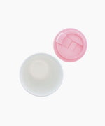Shot from above, the white inside of the mug next to the pink lid. The lid has a flip cover for the drinking hole.