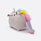 Quarter view of the Pusheenicorn plush, facing the left, standing in a whitespace. The mane starts behind Pusheen’s right ear, and runs down the middle of her back all the way to her tail. 