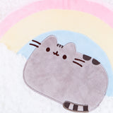 Close up of the Rainbow Pusheen Plush Pillow. Pusheen is embroidered into the pillow, sitting with her feet tucked in and her tail curled around the front. Pusheen is made of the same smooth plush fabric as the rainbow. Pusheen partially sits on top of the cloud, which is made of a curlier, fuzzier fabric.