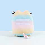 Back view of the Rainbow Pusheen Plush in front of a light blue background. Pusheen's two back stripes are white and embroidered into the plush. Pusheen's tail is a light pastel pink with white stripes. The plush is in front of a light blue background.