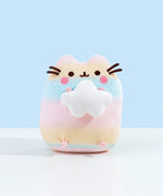Pusheen colored in a pastel gradient, alternating between pink, yellow and blue. Pusheen is sitting upright, holding onto a plush white cloud in the shape of a star. Pusheen's stripes, eyes, and a round pink plush by her whiskers are embroidered into the plush. The whiskers are made of dark brown felt and point outwards.