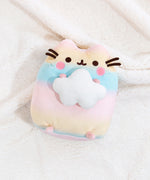 Top view of the Rainbow Pusheen Plush laying down on top of a fuzzy white blanket.