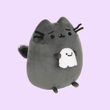 Right quarter view of the Scaredy Cat Squisheen shows Pusheen the Cat holding a light white ghost in her front paws that has a smile on its face. From this view, Pusheen’s puffed out tail can be seen coming out of her back. 