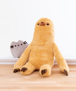 The Sloth plush sitting on the floor, arms uncrossed, with the mini Pusheen plush peeking out from behind him. Sloth’s arms start at the halfway point of Sloth’s body, and reach to the floor. There is a small square Velcro strip on the center of Sloth’s chest and on the palm of his hands that blend in with the color of his fur. Sloth’s legs are like cylinders, with the 3 brown plush claws placed on top of the foot. 
