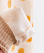 A close up showing the interior of the Pajama pants, which is make of a light white fleece. The cookie pattern is partially visible from the inside out, and the tan ankle cuff is ribbed.