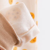 A close up showing the interior of the Pajama pants, which is make of a light white fleece. The cookie pattern is partially visible from the inside out, and the tan ankle cuff is ribbed.