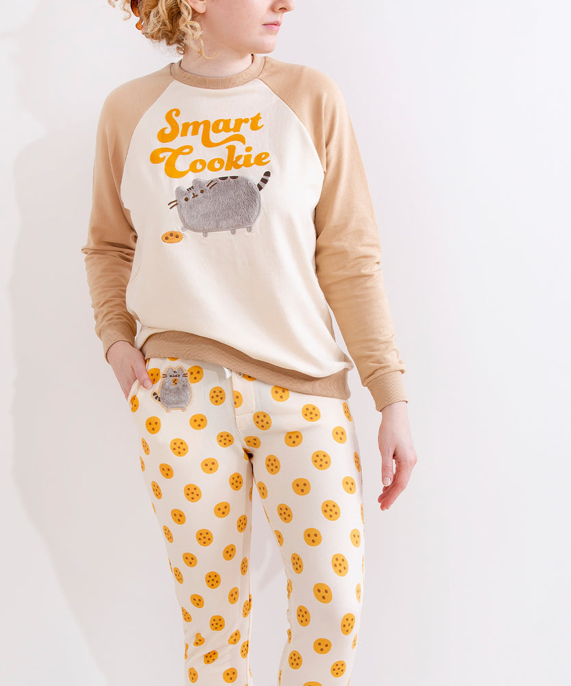 A model wearing the Smart Cookie Pajama Set, with one hand in the pockets of the pajama pant, thumb pointed at the fuzzy patch. The top is fitted around the wrists, but is loose around the waist. The Pajama pants are more closely fitted to the model.