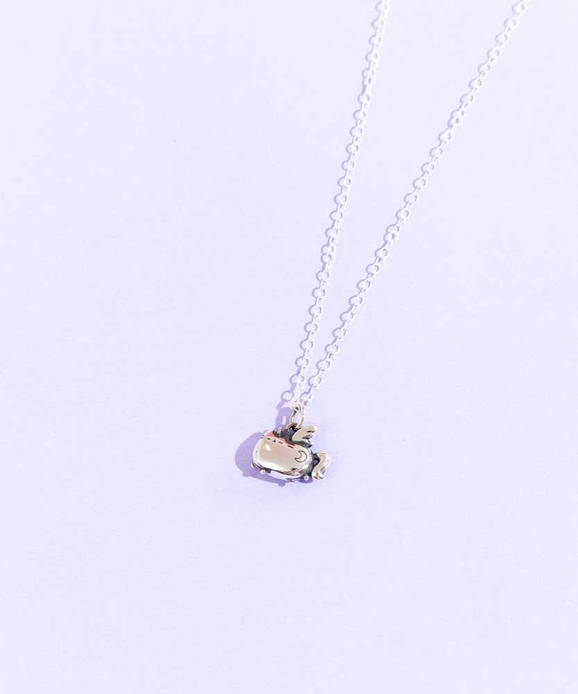 Top view of the Silver Super Pusheenicorn Charm Necklace on top of a light purple background. Super Pusheenicorn’s crescent moon mark is clearly engraved on her right side.
