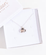 A small white square jewelry box with the lid removed and placed on the top left corner of the box holding the Silver Super Pusheenicorn Charm Necklace. The jewelry lid features the Pusheen the Cat logo printed in silver.