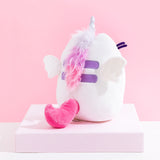 Back view of the Super Pusheenicorn Plush on top of a white square pedestal, in front of a pink background. There is a multicolor mane directly behind Super Pusheenicorn’s horn, colored light purple, purple and pink, going over Pusheen’s Back stripes and ending at the bottom stripe. Pusheen’s back stripes are embroidered in a dark purple, and besides them are two plush wings. Super Pusheenicorn has a solid pink plush tail that curves upwards.