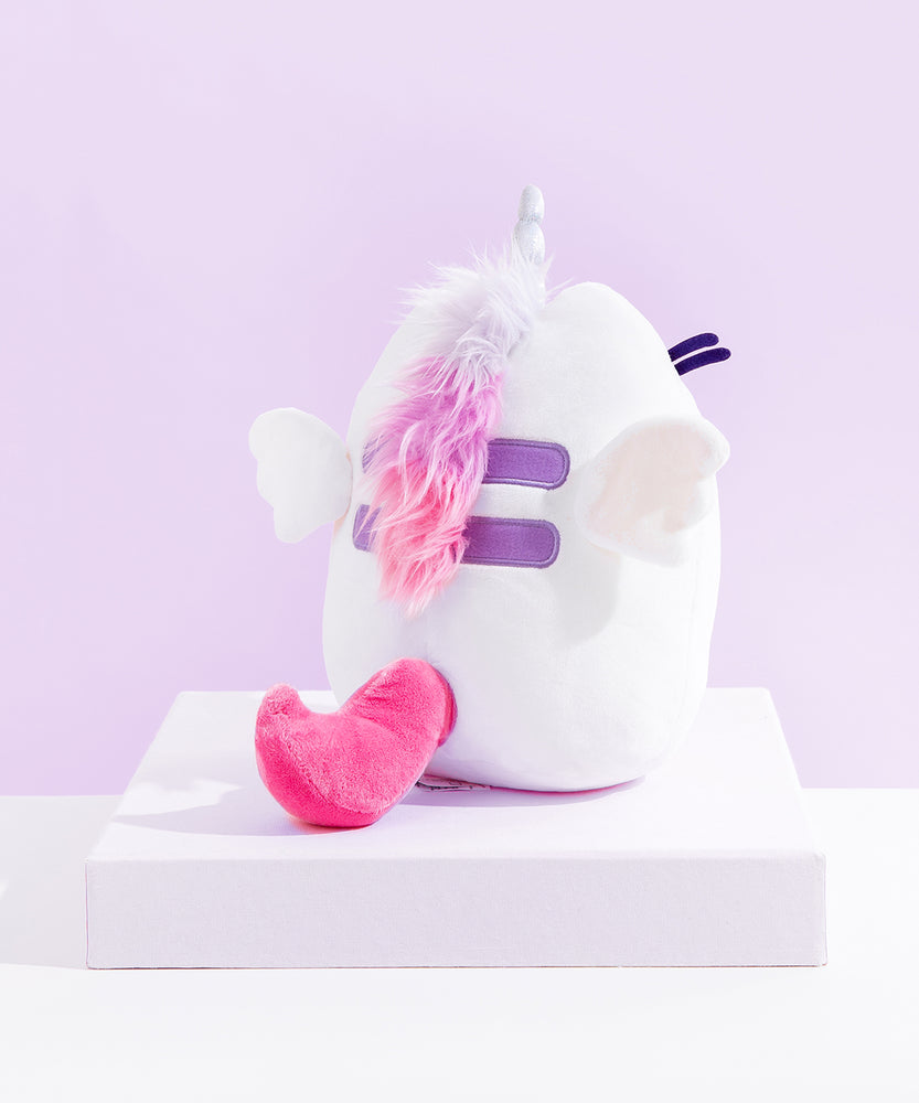 Back view of the Super Pusheenicorn Plush on top of a white square pedestal, in front of a light purple background.