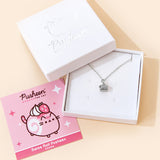 A small white square jewelry box with the lid removed and placed on the top left corner of the box holding the Silver Swiss Roll Pusheen Charm Necklace. To the left is a pink square card insert featuring an illustration of the Swiss Roll Pusheen. The jewelry lid features the Pusheen the Cat logo printed in silver.