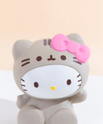 Closeup of the Hello Kitty Jumbo Squishy’s head and costume hoodie in front of a pale yellow background. Hello Kitty’s face and Pusheen’s face and stripes are printed onto the squishy, while Hello Kitty’s dot nose, Pusheen hood, ears and hairbow are sculpted parts of the squishy.
