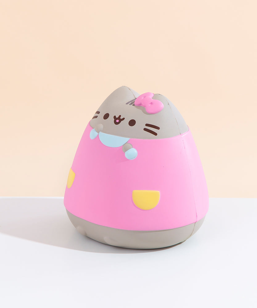 Quarter view of the Pusheen Jumbo Squishy facing to the left, seated on a white floor in front of a pale yellow background. There is a visible seam running down the sides of the Jumbo Squishy. Pusheen’s nub feet are slightly more visible from this angle.