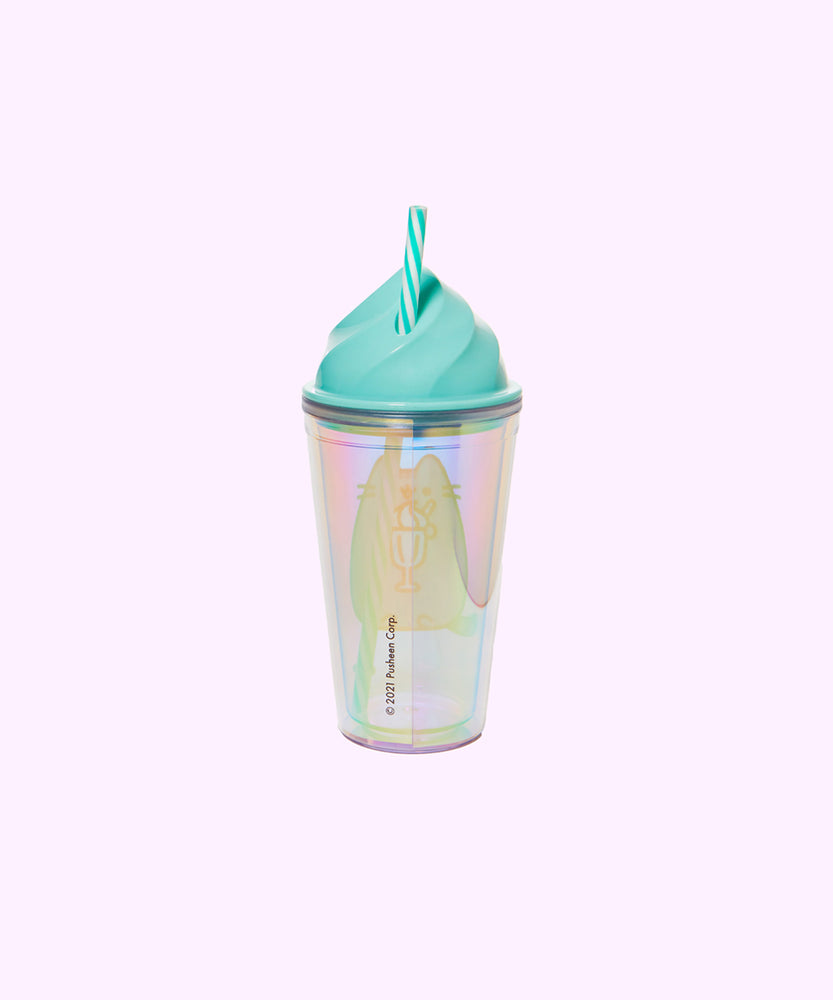 Back view of Whipped Sweet Tumbler. The iridescent finish of the cup allows you to see the Pusheen graphic on the reverse side of the cup. On the back of the cup is the copyright information. In this view, the teal and white striped straw can be seen coming out of the imitation whipped cream top of the cup. 