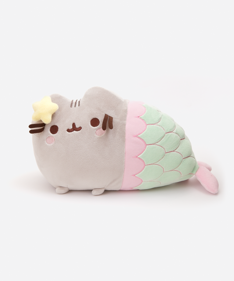 The Mermaid Pusheen Plush in a white space. The right side resembles the standard Pusheen with her feet on the floor, save for the embroidered pink cheeks underneath her eyes and the plush yellow star attached to her left ear. The mermaid tail starts halfway through the plush, with a pink scallop rim before the seafoam green tail with scale lines embroidered in pink. The tail tapers down to a plush pink fin that pokes out to the right.