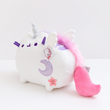Quarter view of the Super Pusheenicorn Musical Plush facing the left in front of a white background. Super Pushenicorn’s mane starts behind her horn, goes behind her right ear, and runs straight down her back through the  two back stripes. It ends close to her tail. There is a white plush wing on each side of the mane. The plush tag is right bright the tail.