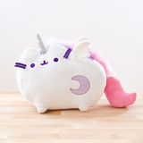 The plush features an all-white Pusheen standing on her legs, a unicorn horn in between her ears. She has white plush wings around the edge of her top back stripe, and a light purple sparkly moon on the lower right of her front body. Super Pusheenicorn’s embroidered details such as her eyes, mouth and head stripes, and her felt whiskers are all a dark purple. She has a fluffy multicolor light purple, purple and pink mane running down her back, leading to her solid pink plush tail that curves upwards