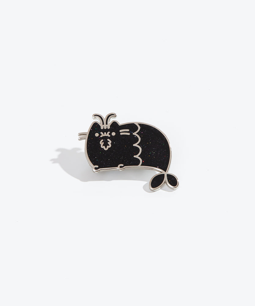 The Capricorn pin on a white background. The pin features Pusheen with a mermaid tail, two curved horns sticking out in between her ears, and a little beard underneath her chewing mouth. The pin is black with multicolor sparkles and a silver outline.