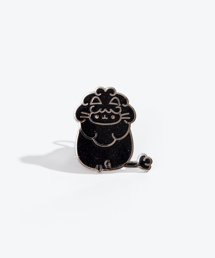 The Leo pin on a white background. The pin features Pusheen with a big lion’s mane and a long tail with a small poof at the end. The pin is black with multicolor sparkles and a silver outline.